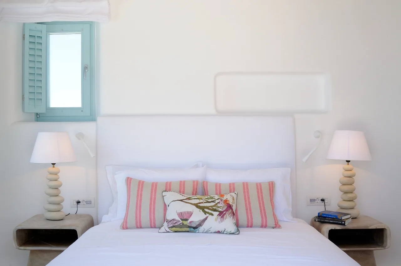 A bedroom with a neatly made bed and matching bedside lamps.