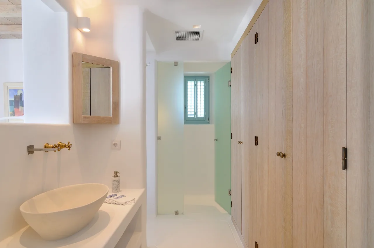 A bright bathroom with a vessel sink and a window at the far end.