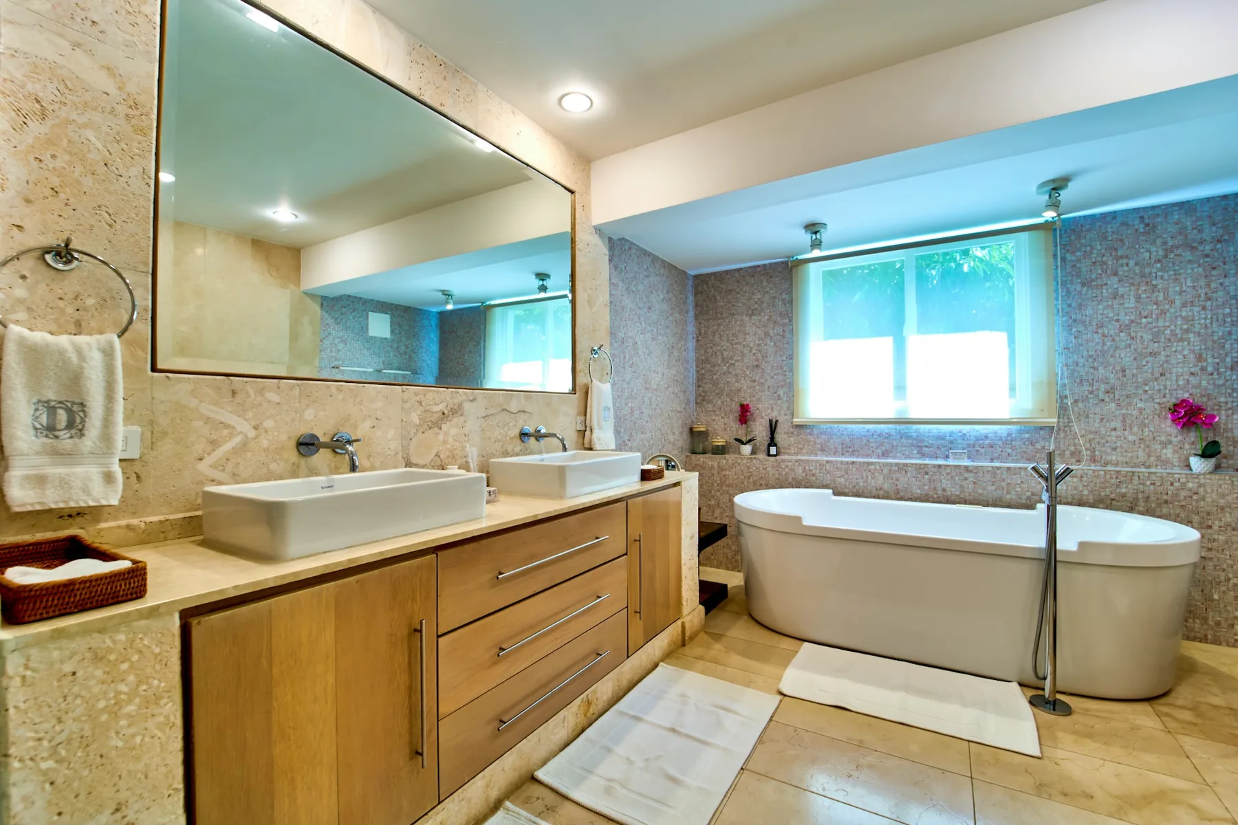Un baño luminoso con bañera, tocador y un espejo grande.