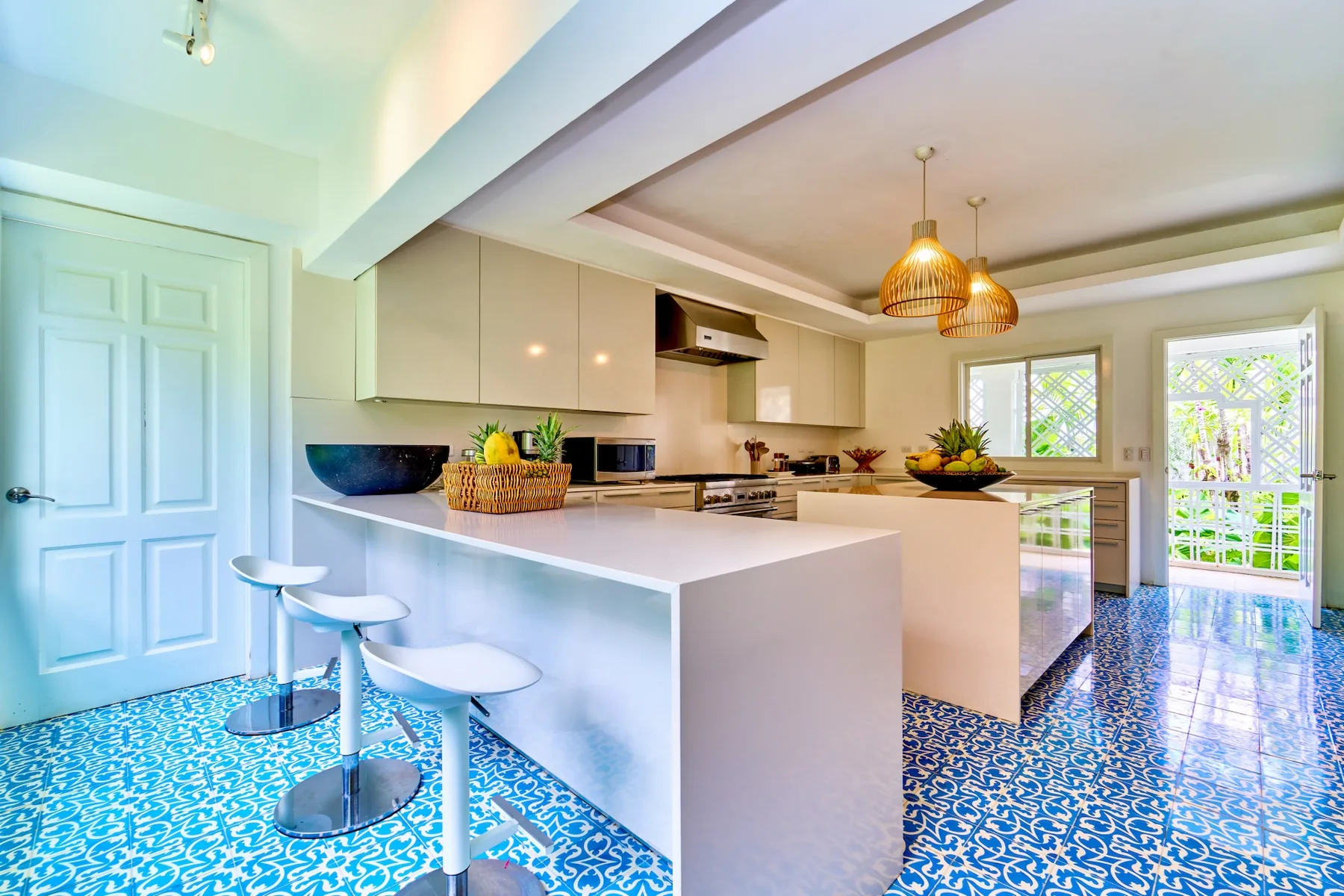 Una cocina luminosa con una isla larga, asientos de barra y suelo estampado.