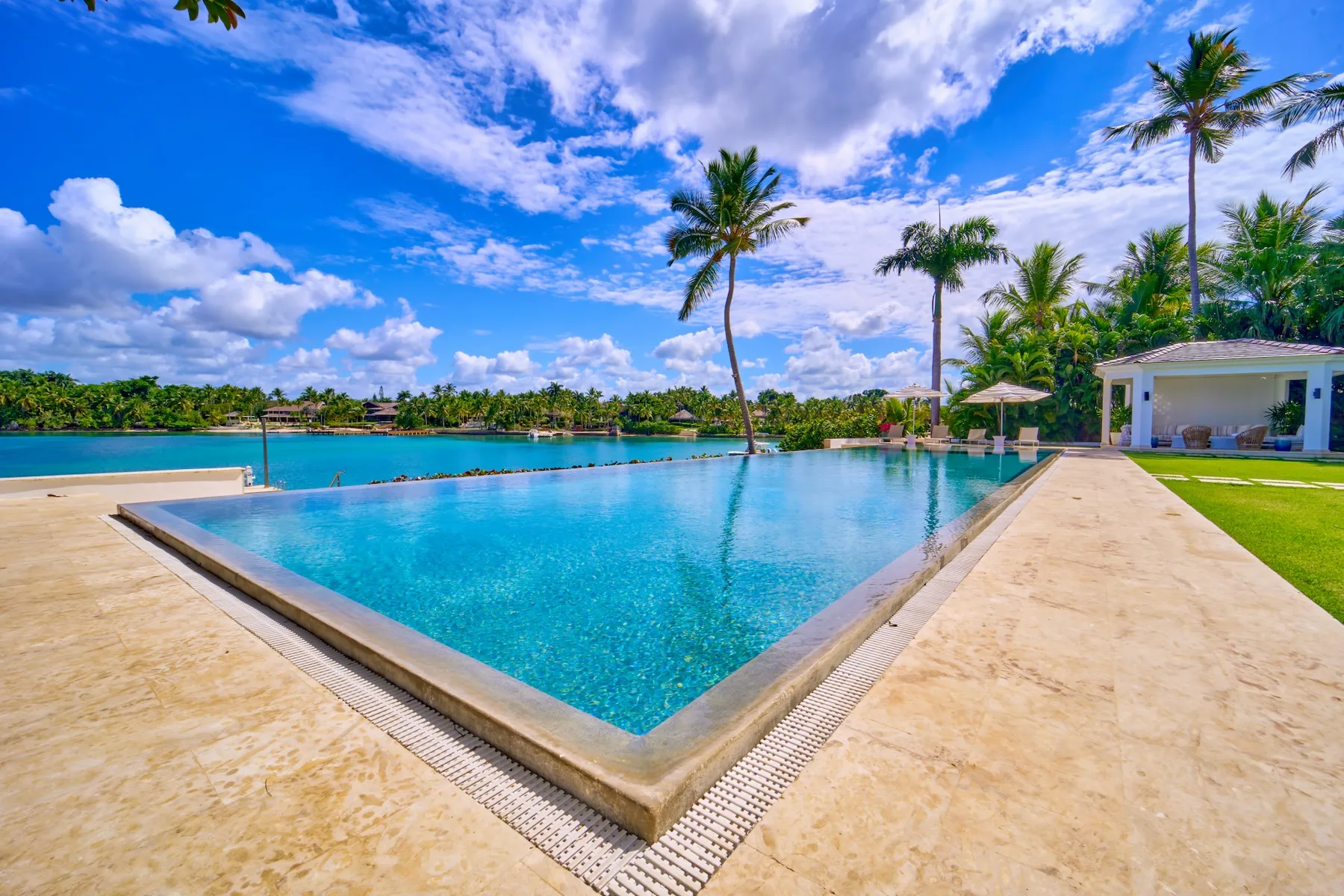 Una piscina da a aguas turquesas, con palmeras y un cielo soleado.