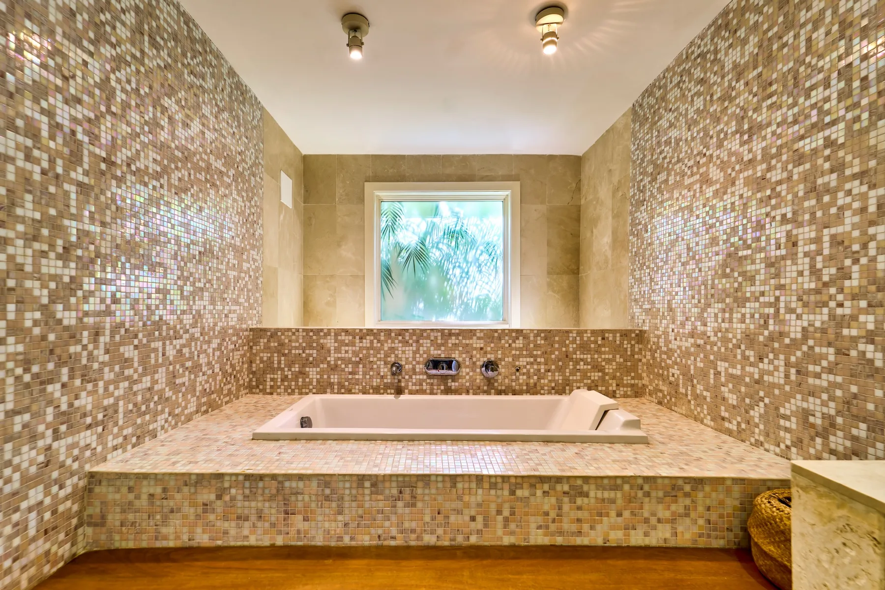Un baño revestido de azulejos tiene una bañera empotrada bajo una ventana.