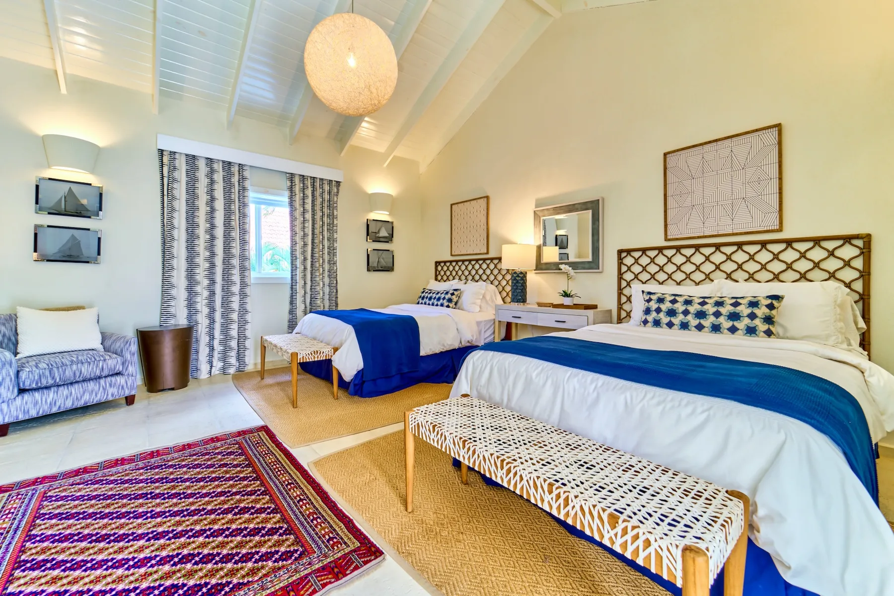 Un dormitorio luminoso con dos camas vestidas con ropa de cama blanca y azul.