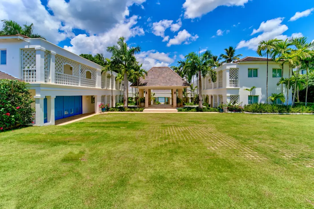 A landscaped lawn leads to a covered entrance between two white buildings.