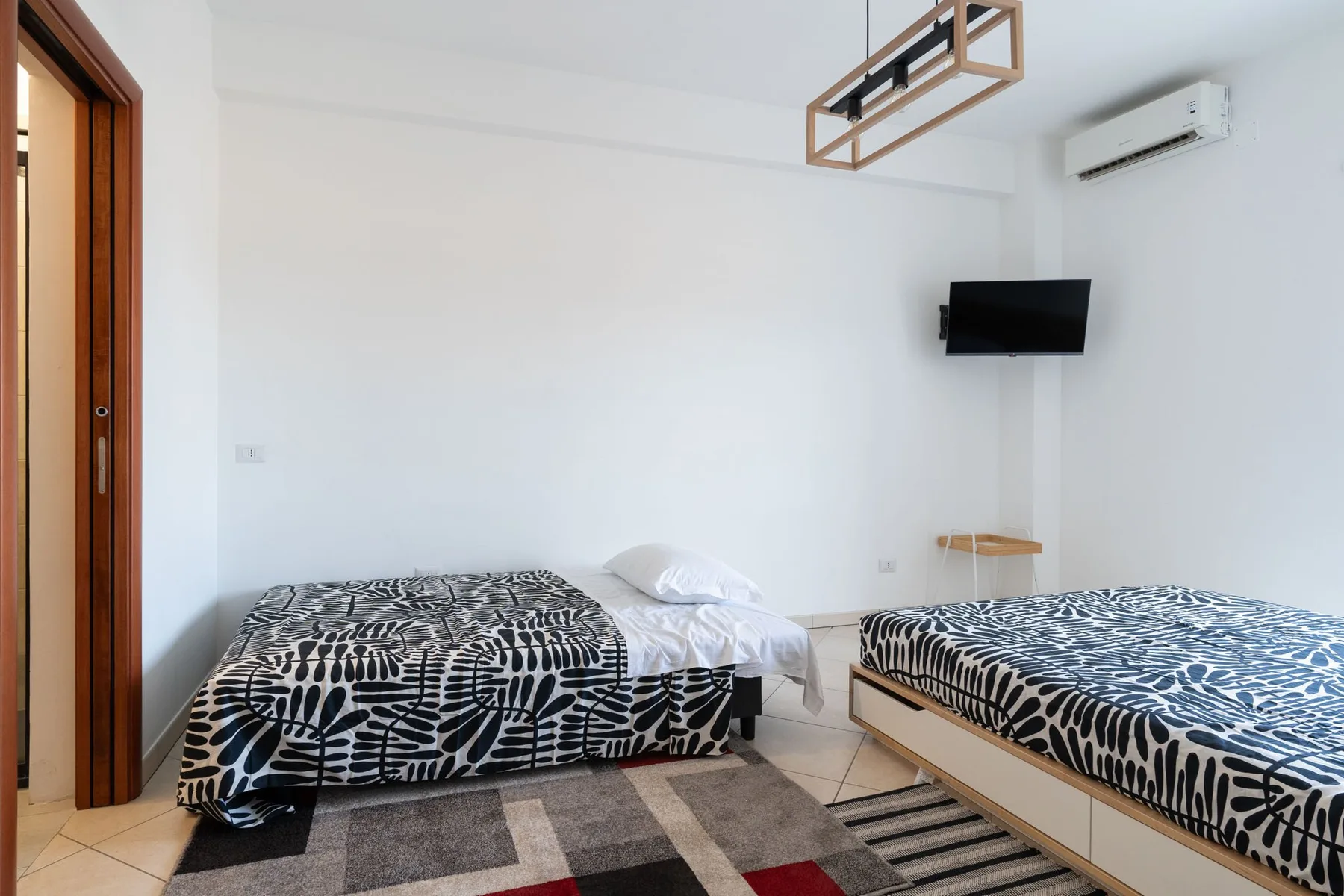 Un dormitorio con dos camas y ropa de cama estampada en blanco y negro.