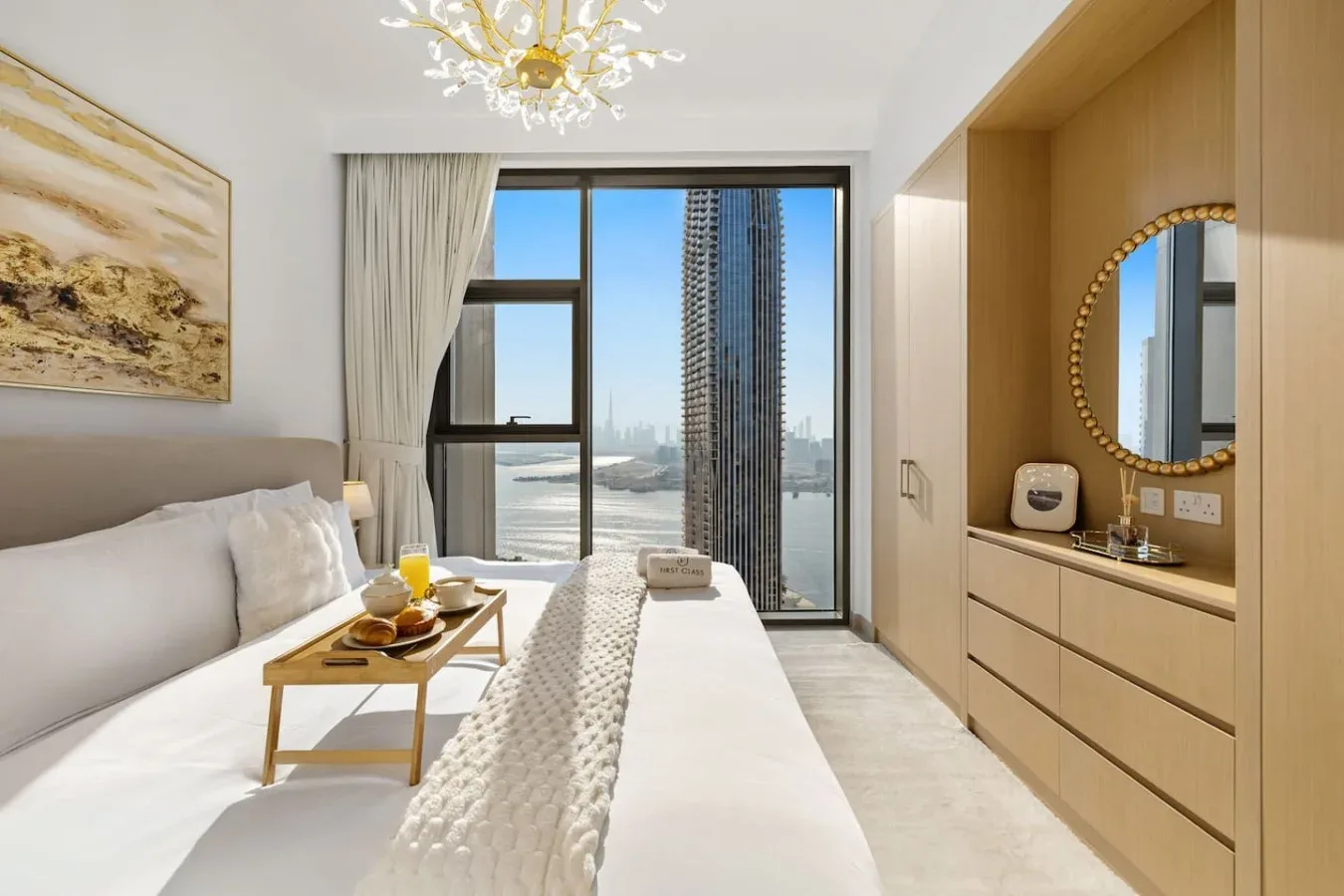 Dormitorio luminoso con cama, mesa auxiliar y grandes ventanas con vistas al agua.