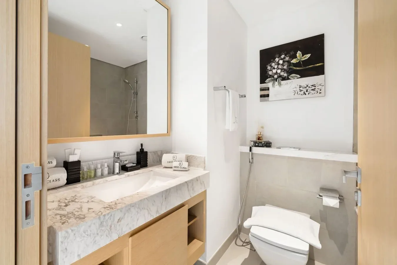 Un baño luminoso con un amplio lavabo, espejo de pared e inodoro.