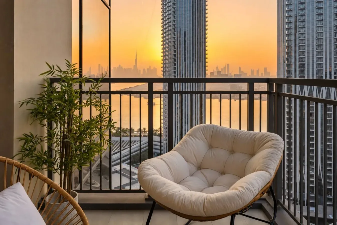 Una zona de estar en el balcón da a edificios altos al atardecer.