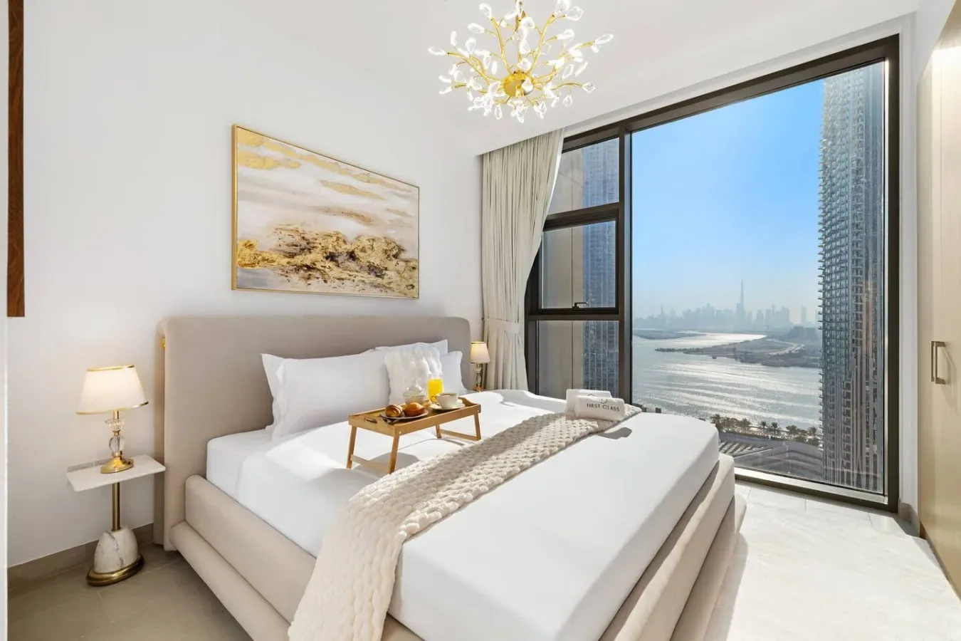 Un dormitorio luminoso con una cama bien arreglada junto a una gran ventana con vistas a la ciudad.