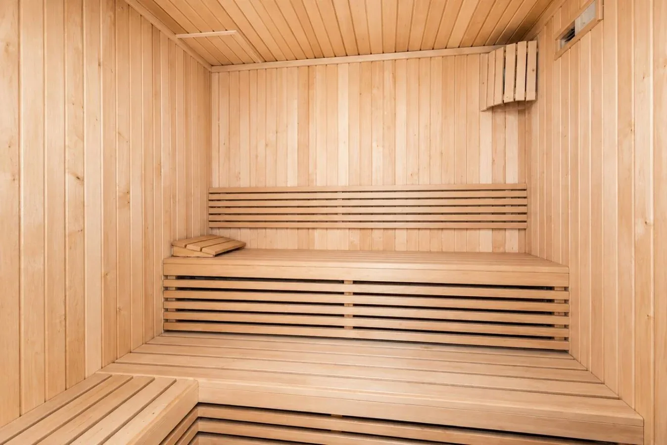 Interior de sauna de madera con bancos escalonados y un pequeño reposacabezas.