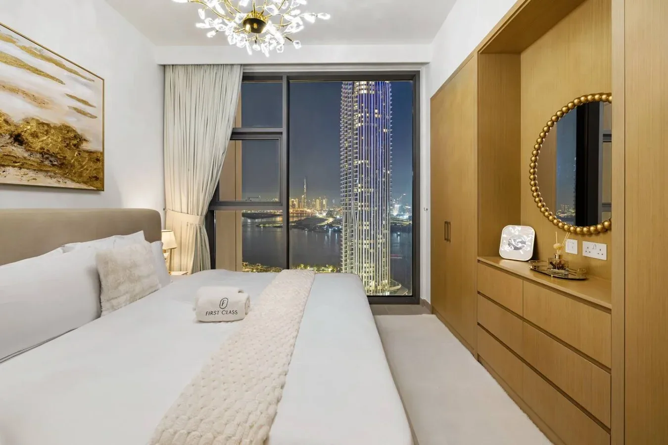 Un dormitorio con una cama grande y ventanales con vistas a las luces de la ciudad.