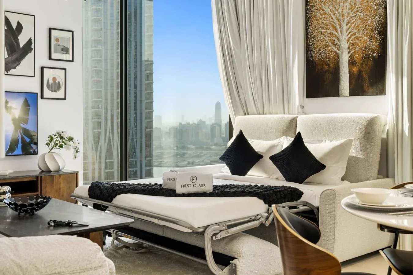 Una luminosa sala de estar con asientos color crema junto a grandes ventanas con vistas a la ciudad.