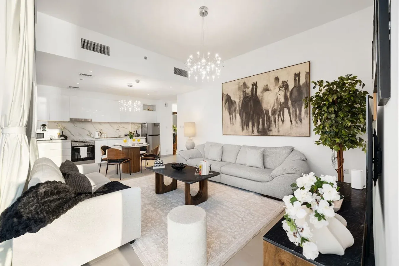 Una luminosa sala de estar de concepto abierto con una zona de asientos gris y cocina contigua.