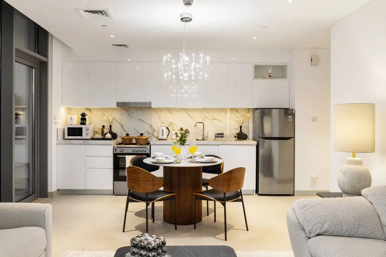 Una cocina moderna y comedor con una mesa redonda y una lámpara colgante.