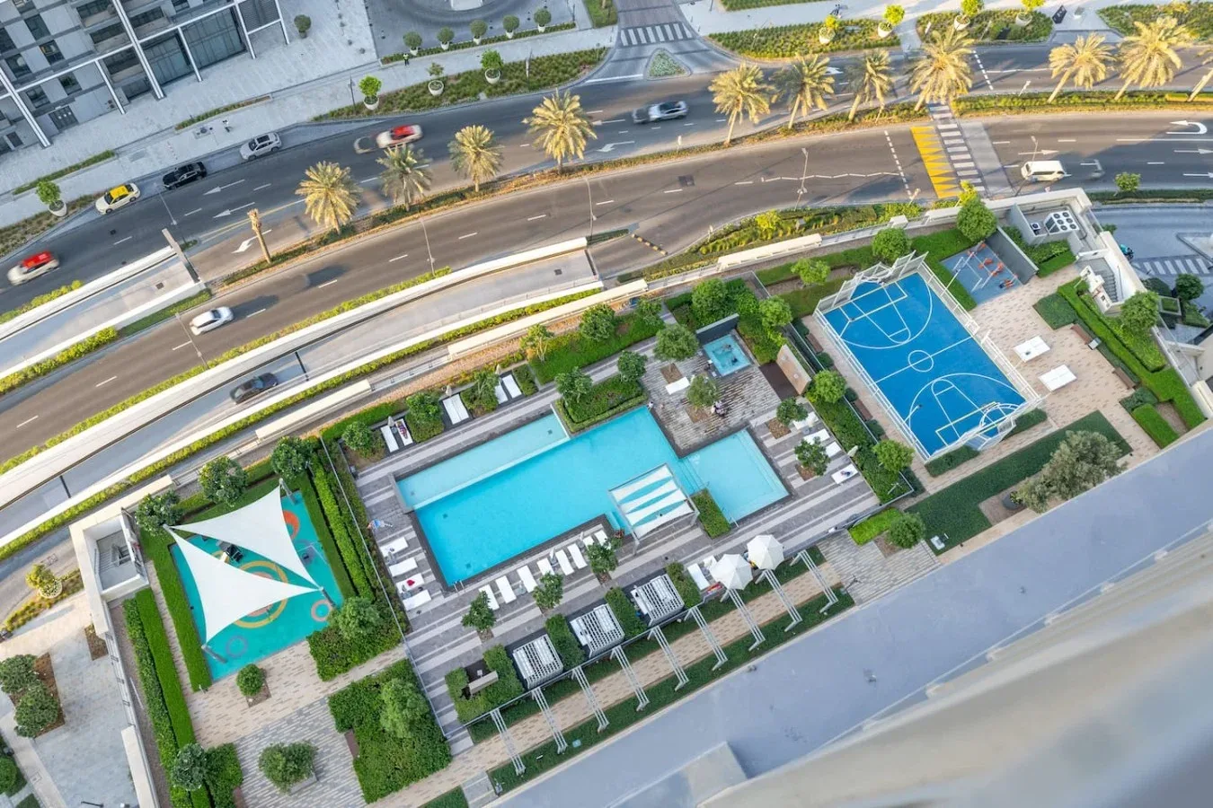 Vista aérea de una zona recreativa ajardinada con piscina y cancha deportiva.