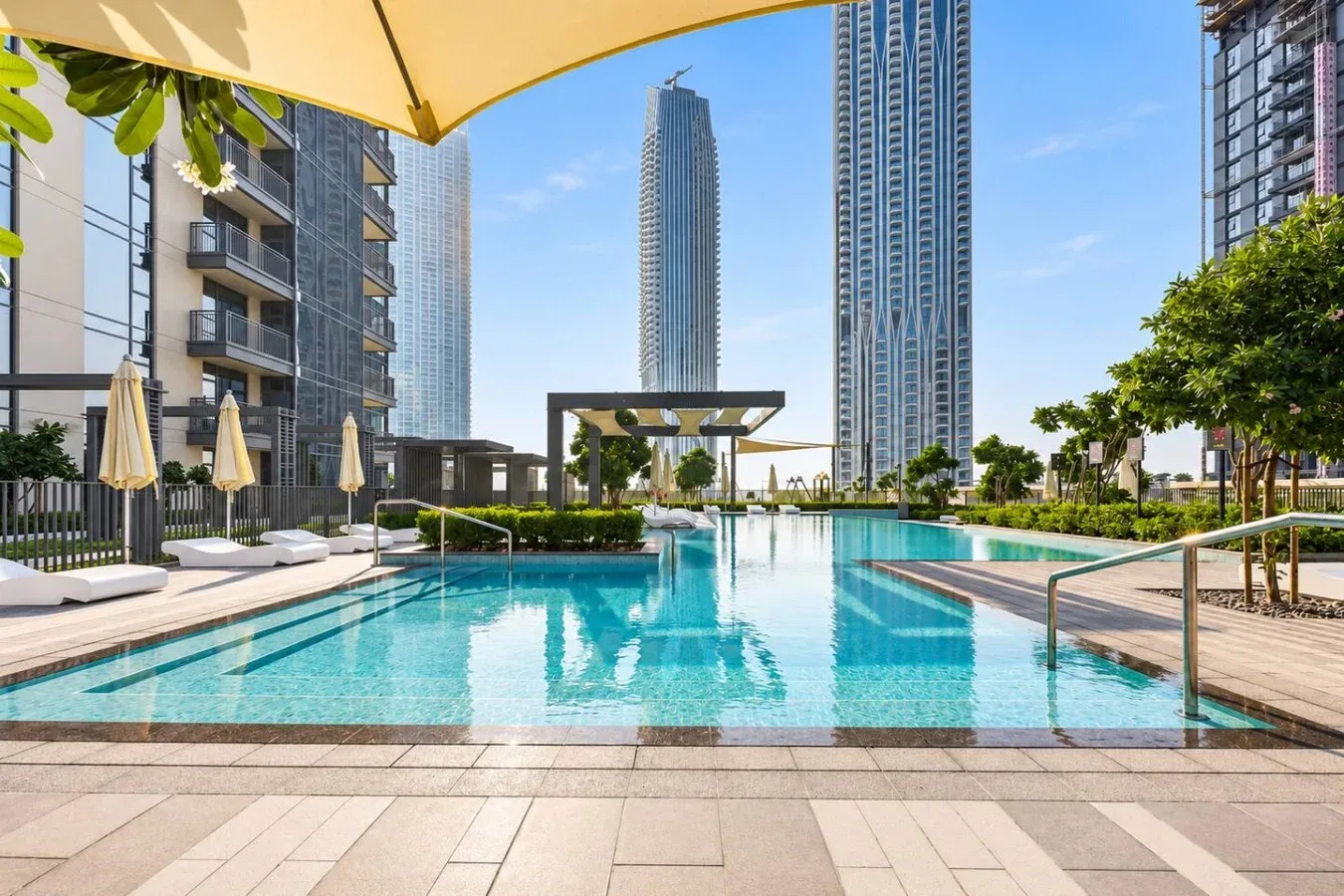 Una piscina en la azotea se encuentra entre edificios modernos bajo un cielo despejado.