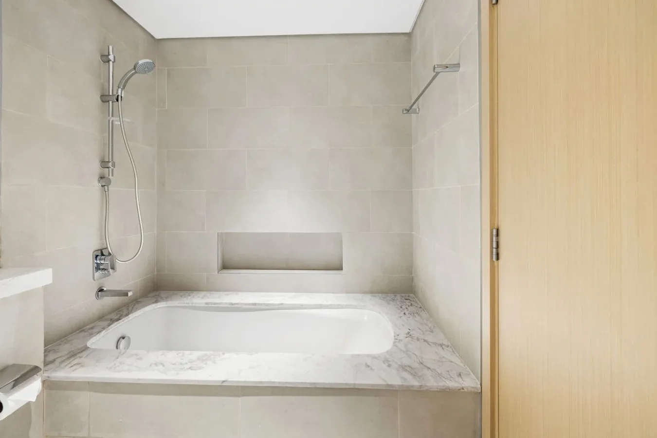 Un baño alicatado con bañera y ducha fijada a la pared.