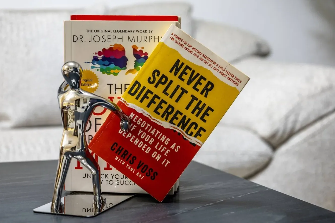 Libros están de pie sobre una mesa frente a un sofá blanco.
