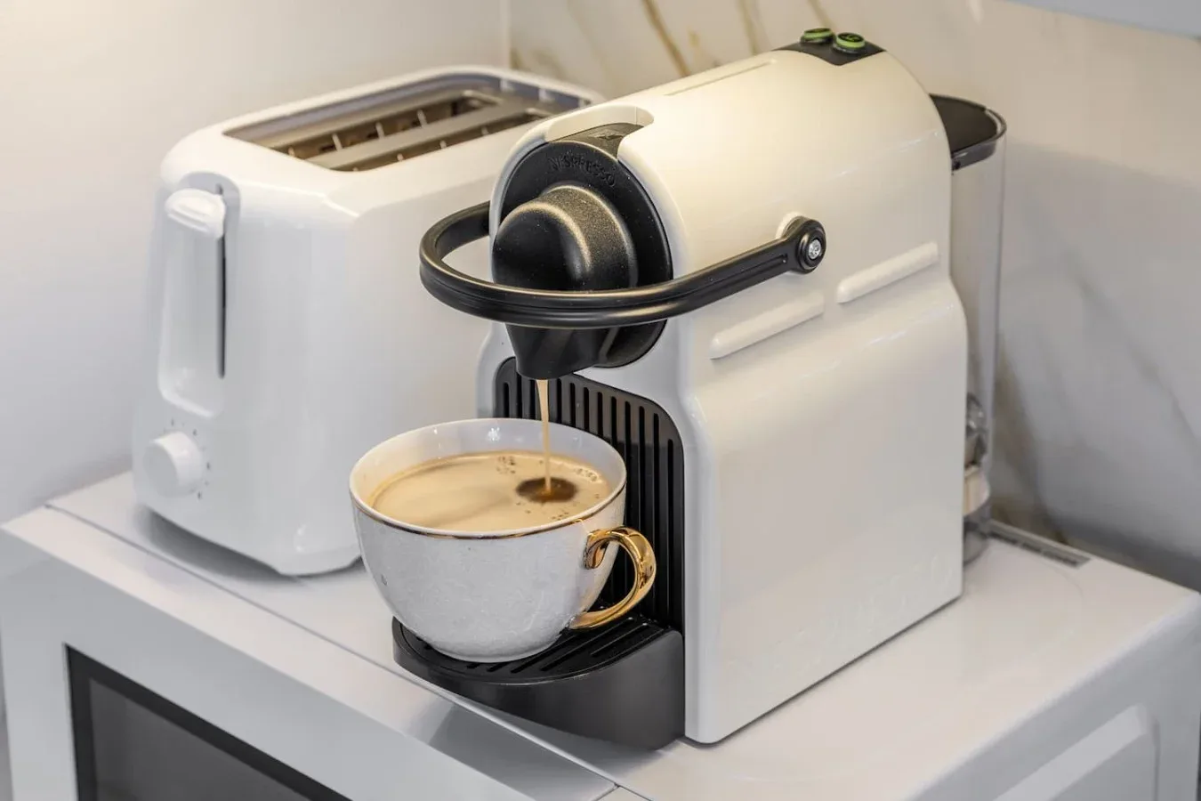 Una cafetera sirve café en una taza sobre una encimera.