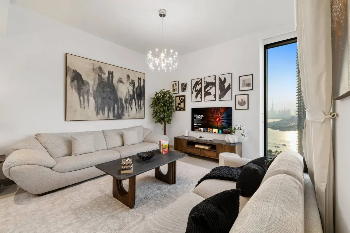 Una sala luminosa con asientos claros, cuadros enmarcados y un televisor.