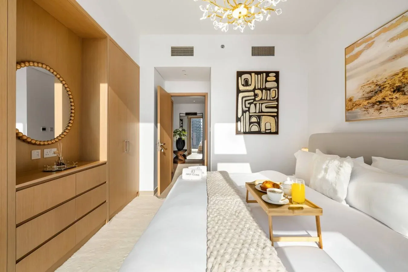 Un dormitorio luminoso con una cama, una cómoda de madera y arte enmarcado.