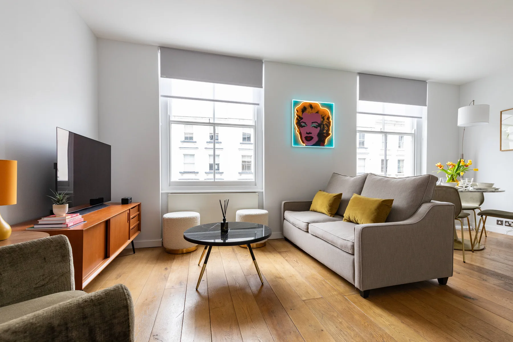 Una sala de estar con asientos, un televisor y grandes ventanas.