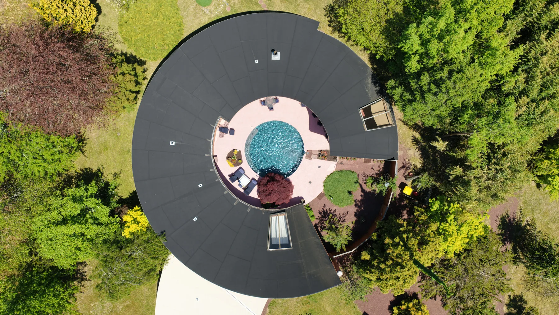 Vista aérea de un edificio con techo circular alrededor de una piscina y un patio.