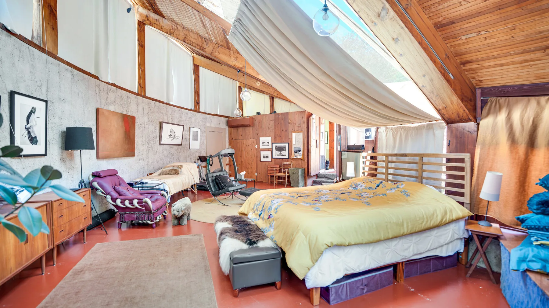 Un dormitorio con una cama grande bajo un techo de madera inclinado.