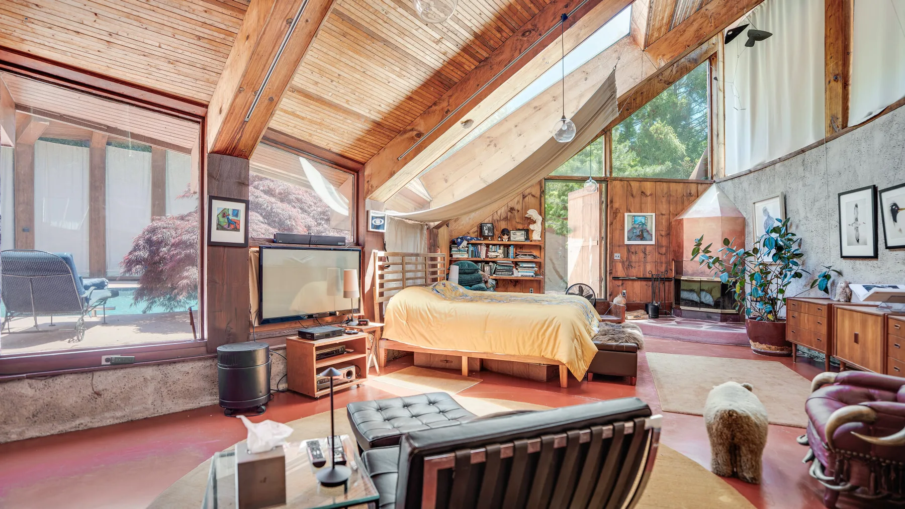 Una amplia sala de estar con una zona para sentarse, televisión y grandes ventanas.