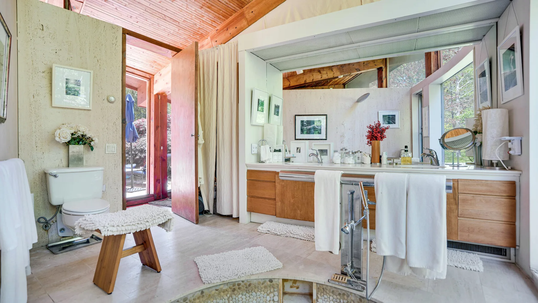 Un baño luminoso con un lavabo amplio, espejos y un techo de madera.