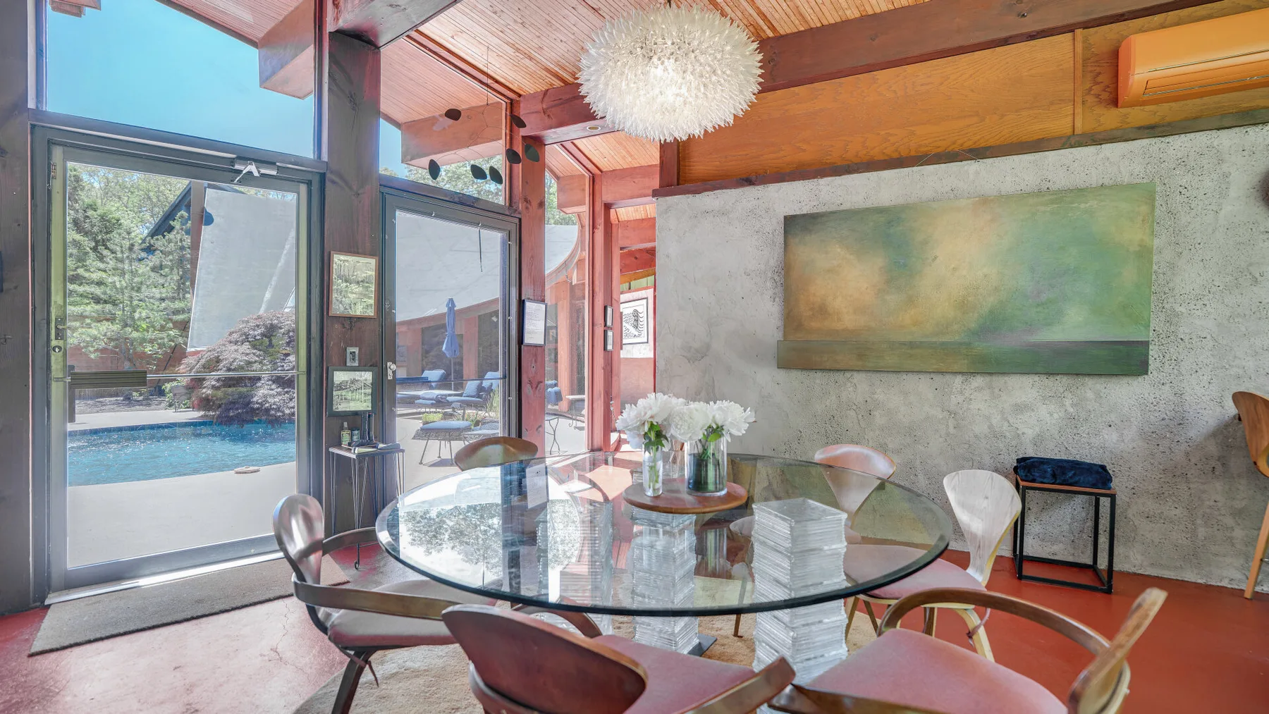 Comedor con mesa de vidrio y puertas corredizas con vista a una piscina.