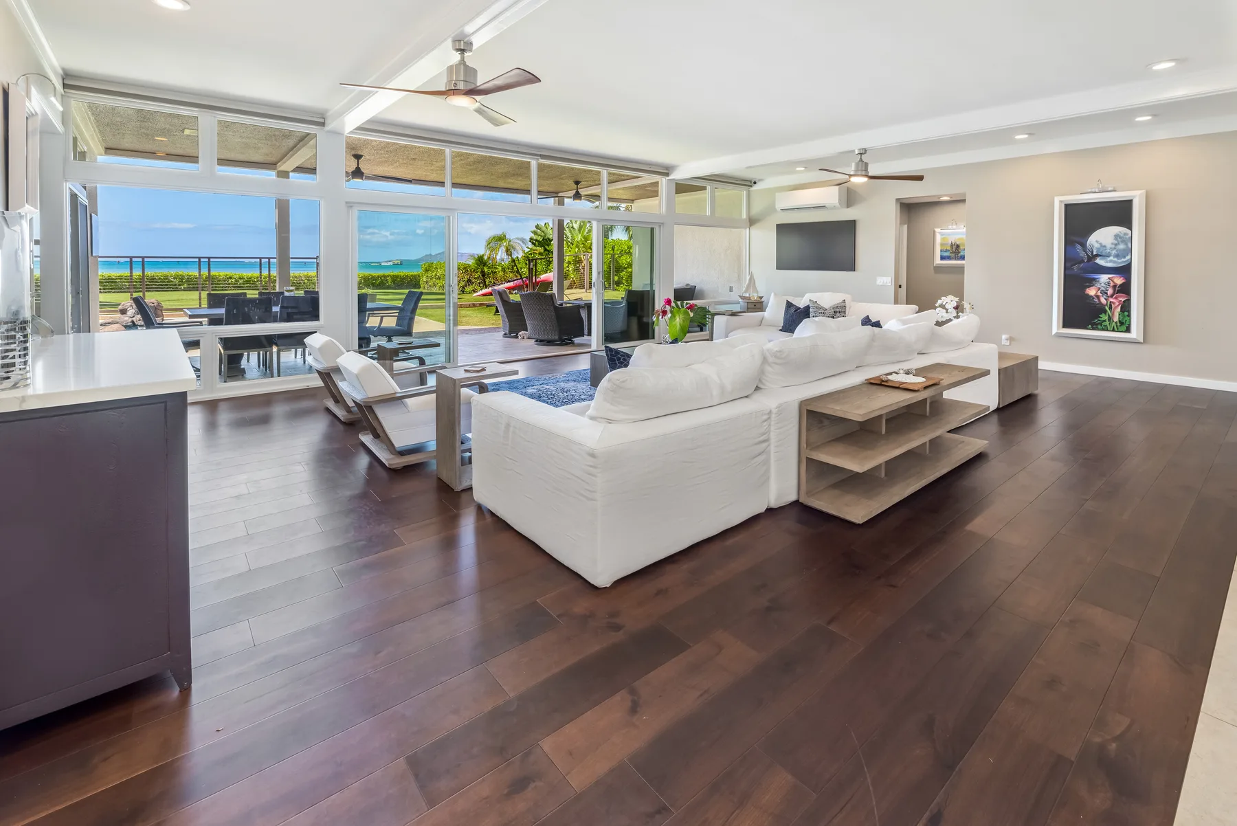 Una sala luminosa con asientos blancos y grandes ventanales con vistas al agua.