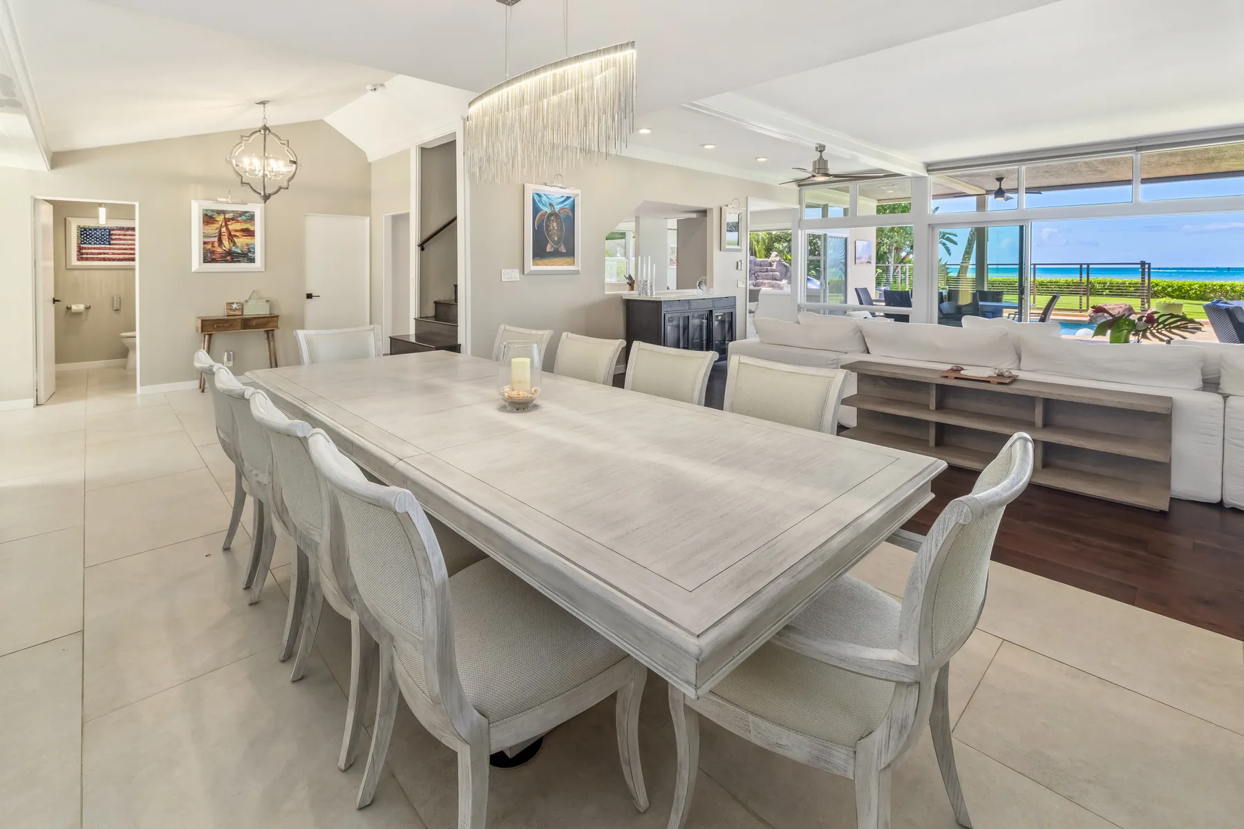 Un comedor luminoso con una mesa larga y asientos junto a una sala de estar abierta.