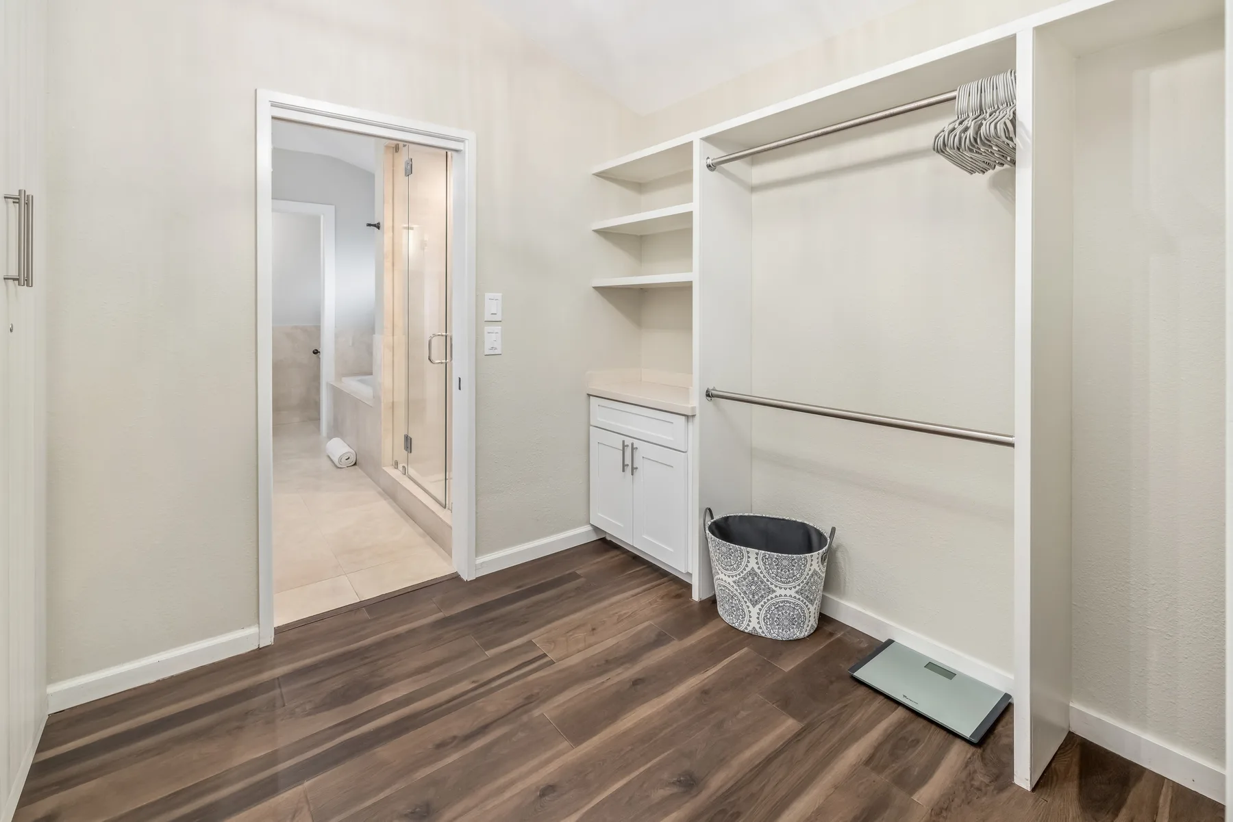 Un vestidor con estantes abiertos y una puerta hacia un baño.