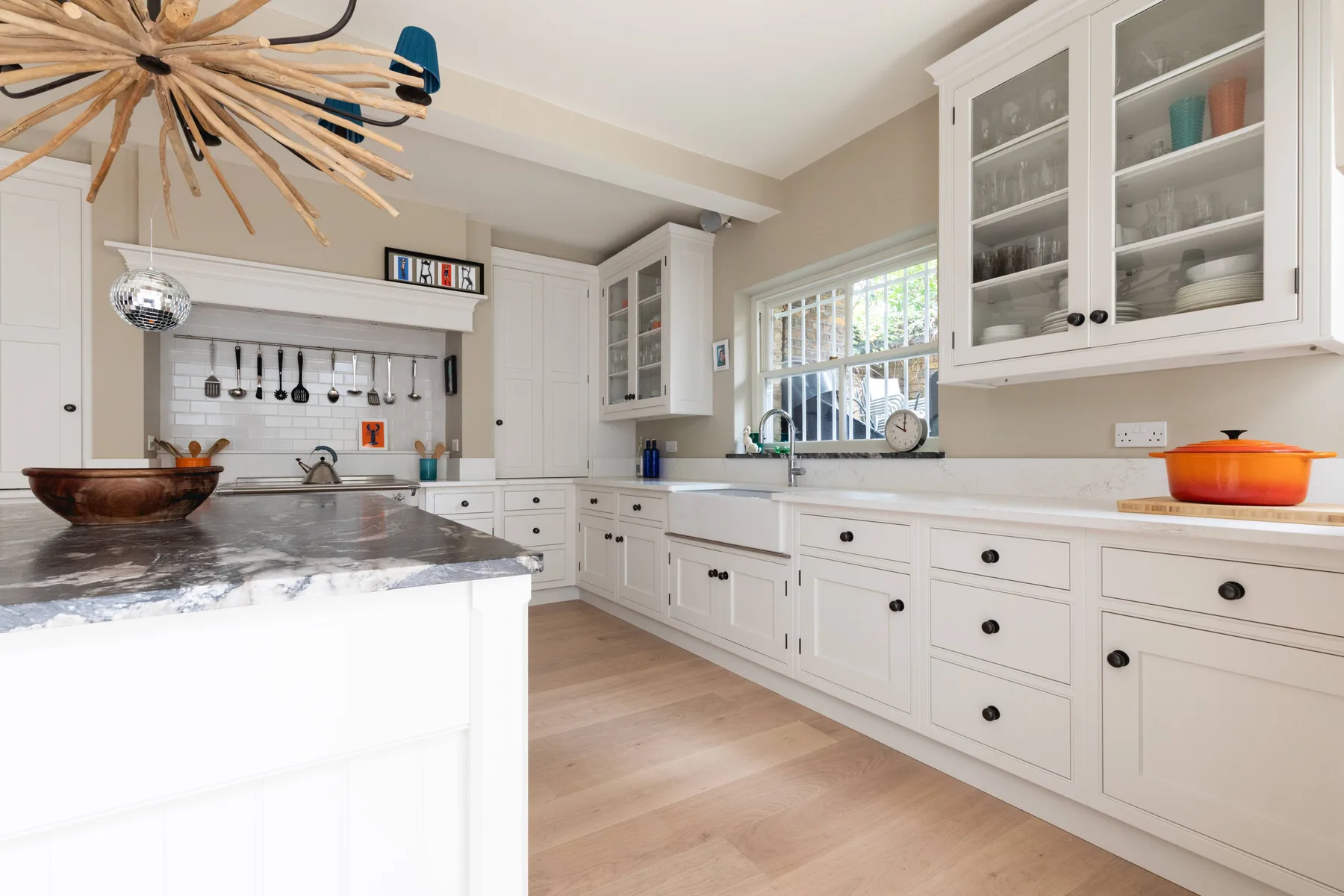 Una cocina blanca y luminosa con armarios de puertas de vidrio y una amplia isla central.