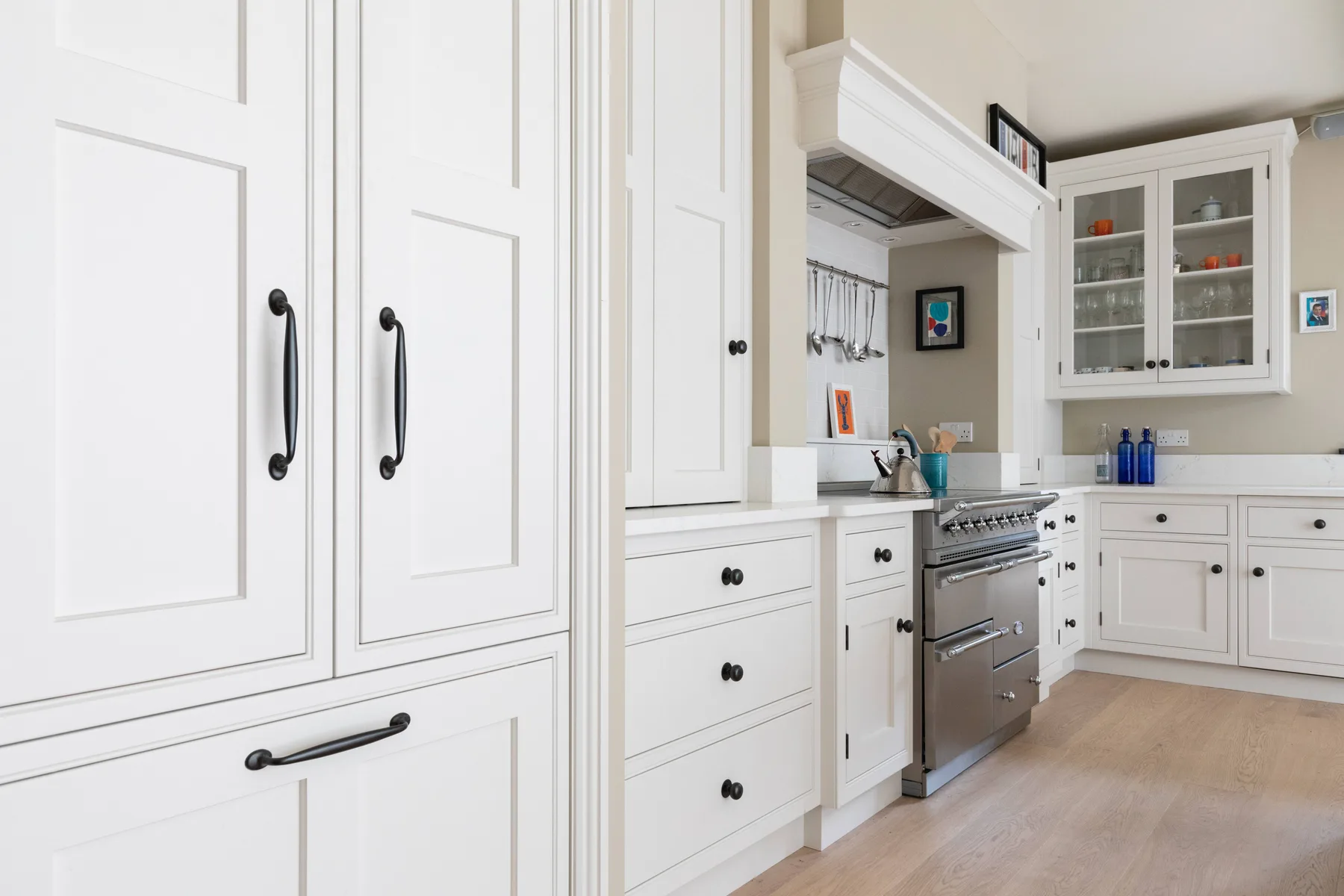 Una cocina luminosa con gabinetes blancos, una estufa de acero inoxidable y piso de madera clara.
