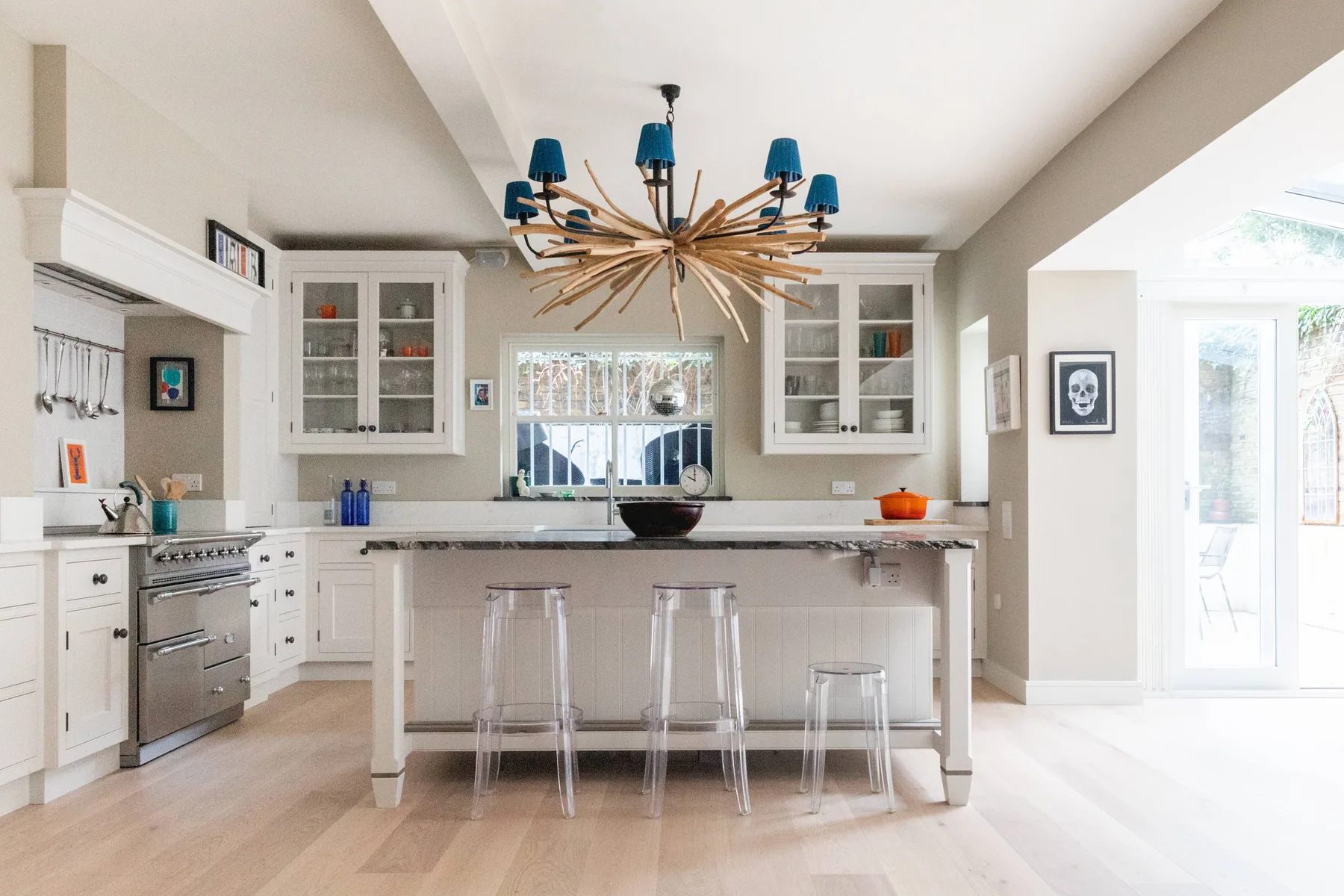 Una cocina luminosa con una isla central y taburetes transparentes.