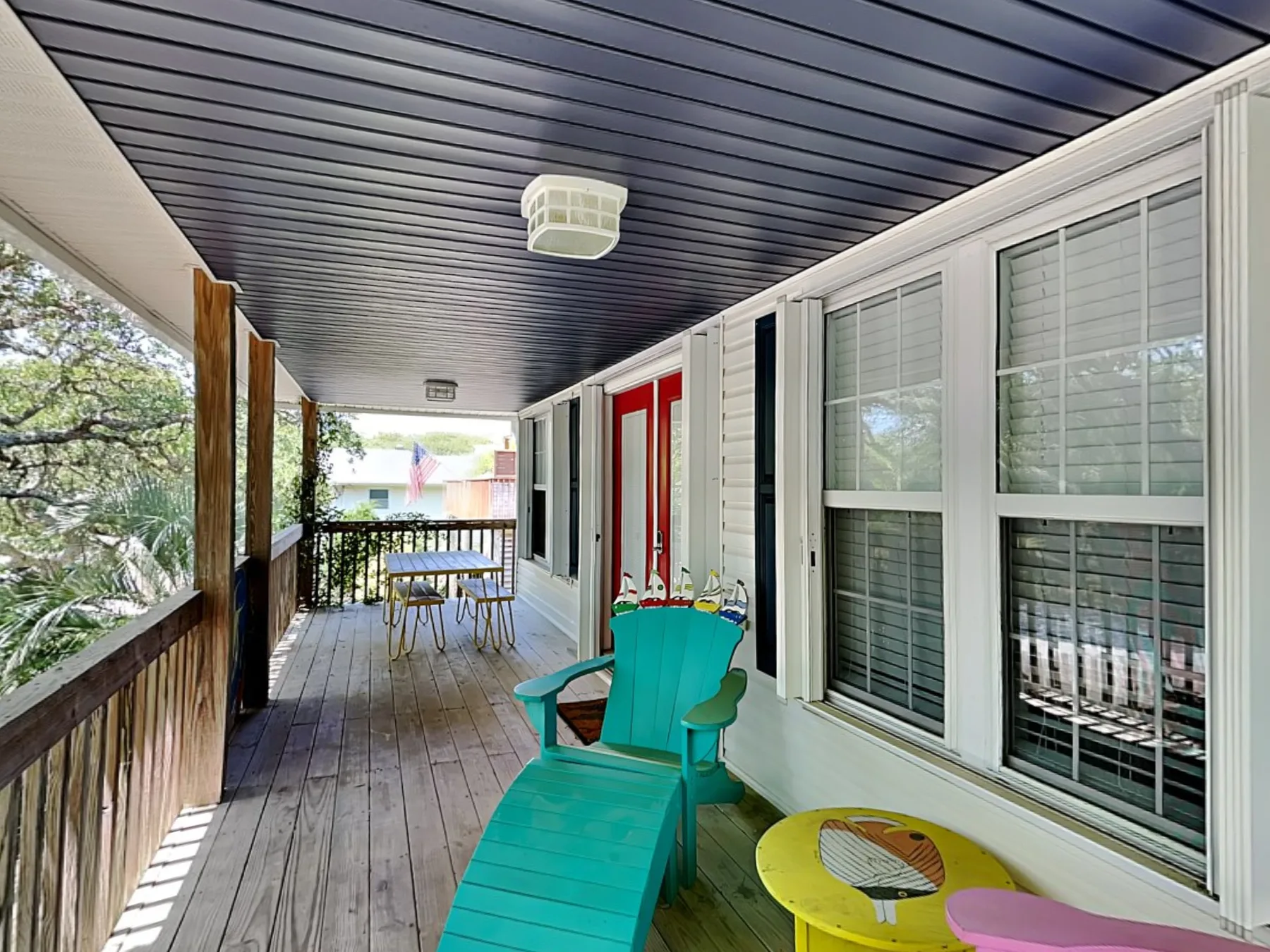 A covered porch with turquoise seating and large windows along one side.
