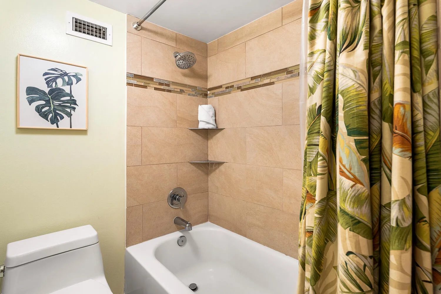 Un baño alicatado con bañera, grifería de ducha y una cortina estampada.