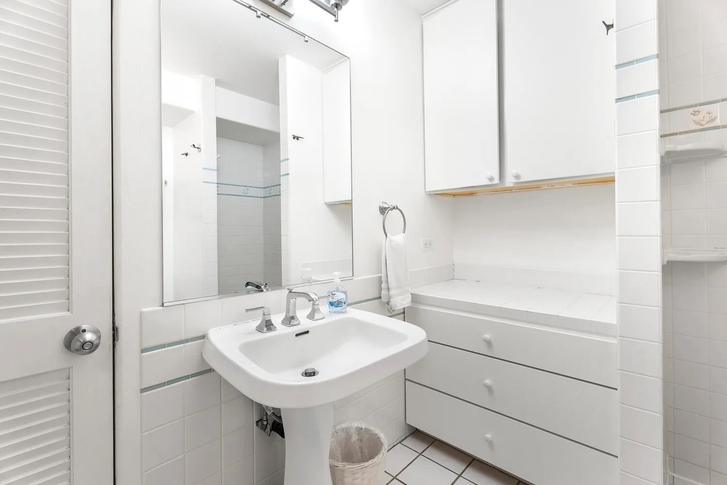 Un baño luminoso con lavabo, espejo y almacenamiento integrado.