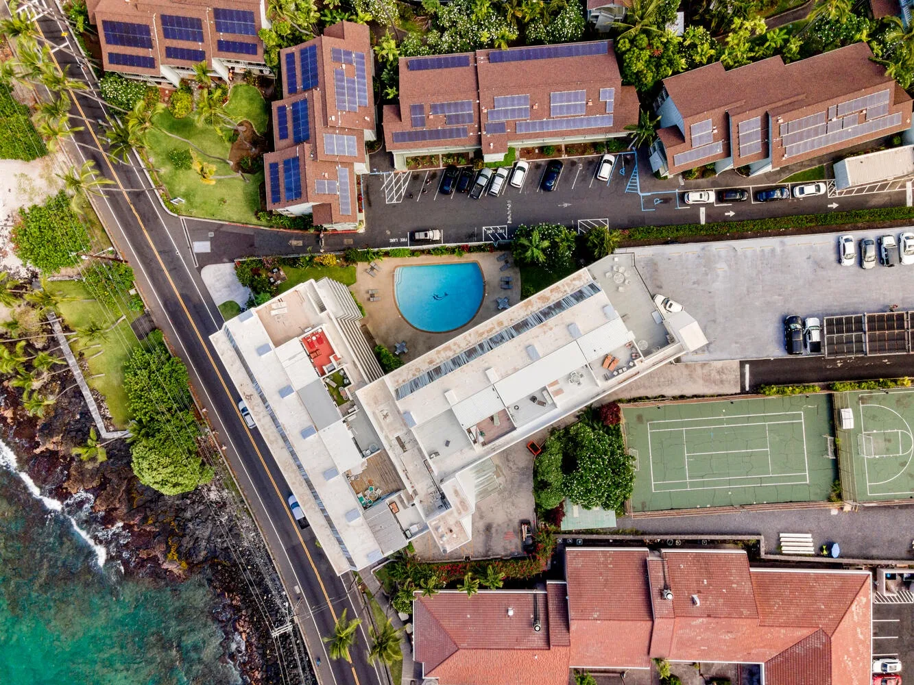 Vista aérea de una propiedad costera con edificios, una piscina y una cancha deportiva.