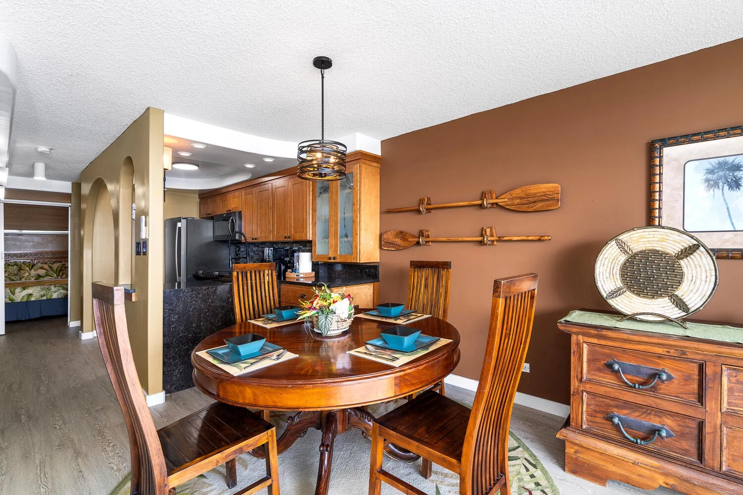 Comedor con una mesa redonda de madera y sillas junto a una cocina.