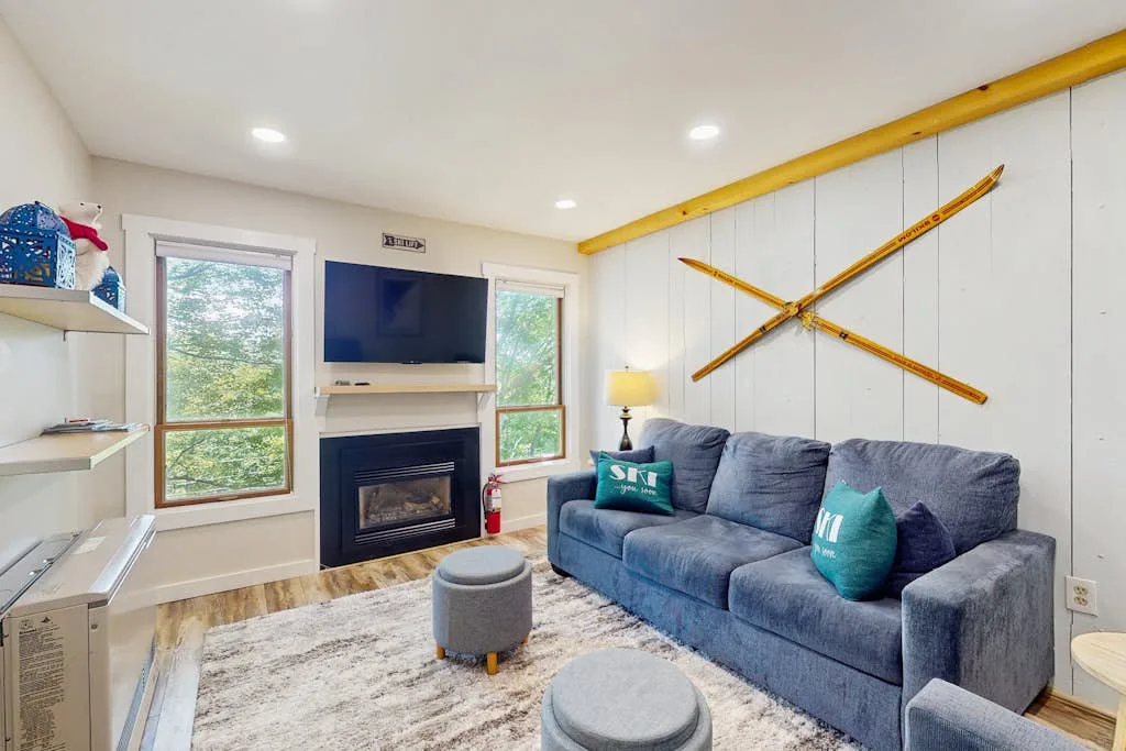 Una sala de estar con un sofá azul, televisor y chimenea.