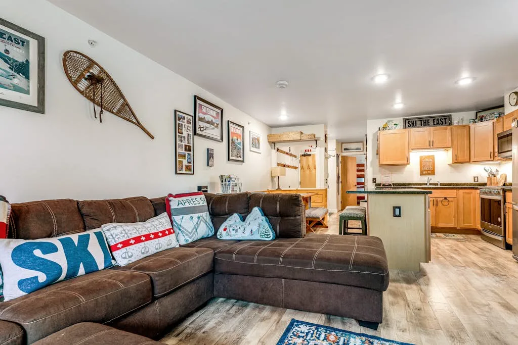 A living room with a sectional seating area and an open kitchen.