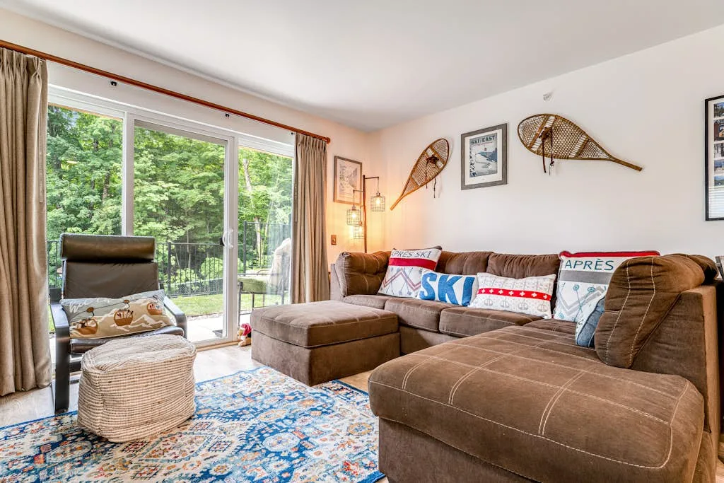 A living room with sectional seating beside large windows overlooking greenery.