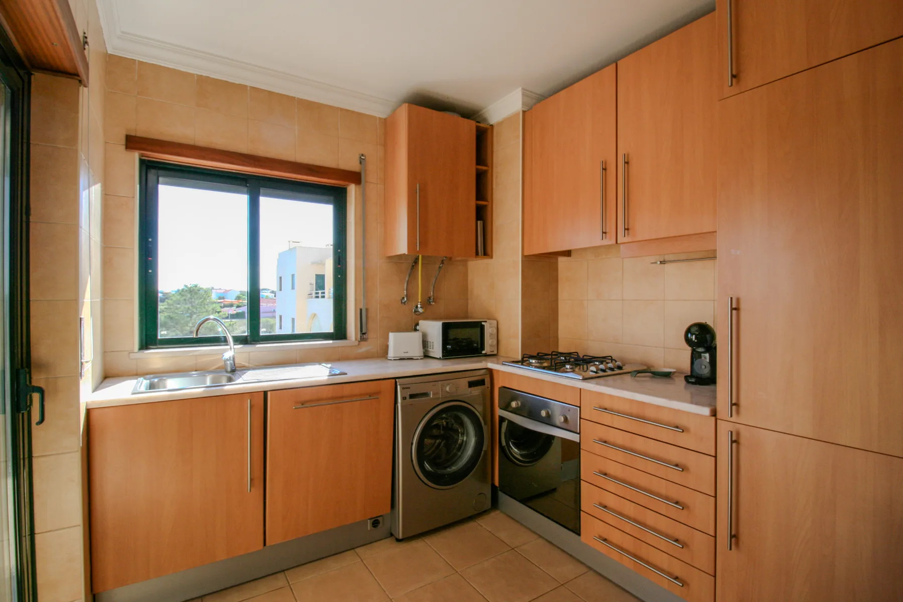 A kitchen with wooden cabinets, a sink, and cooking appliances.
