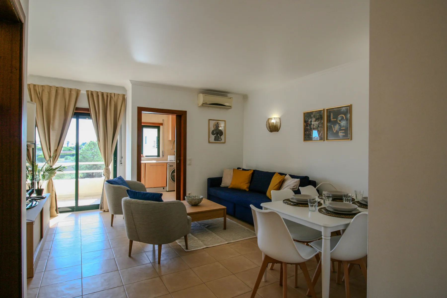 A living and dining area with blue seating and a table beside glass doors.