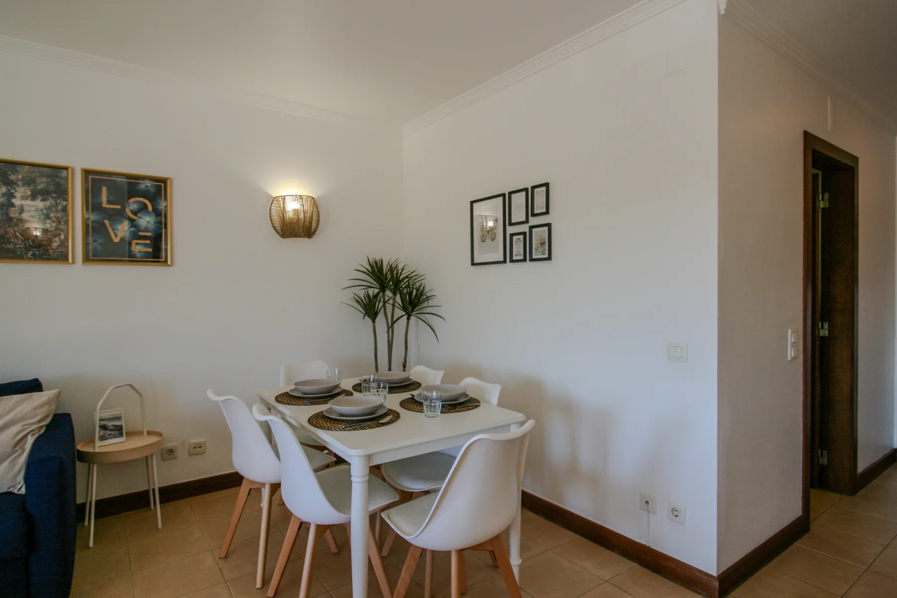 A dining area with a table set beneath framed wall art.