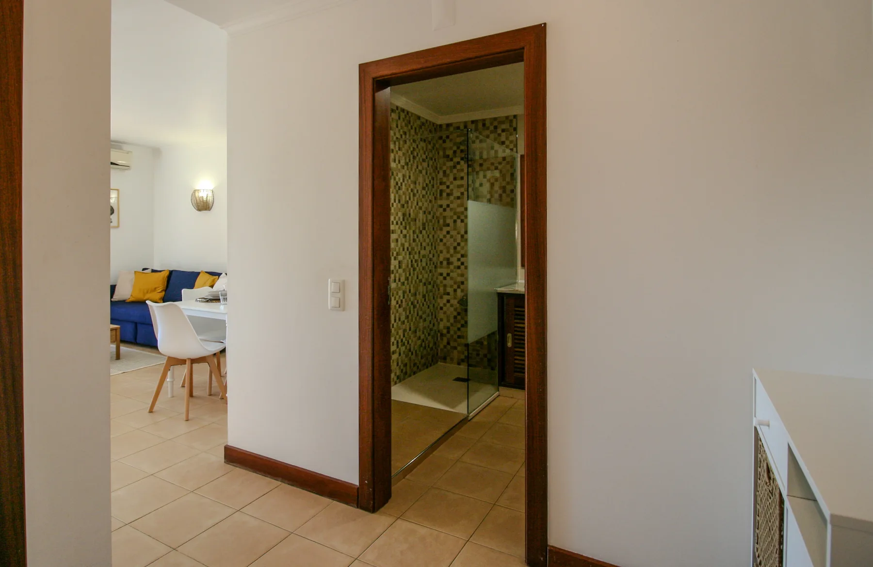 A tiled interior hallway opens onto a bathroom and a furnished living area.