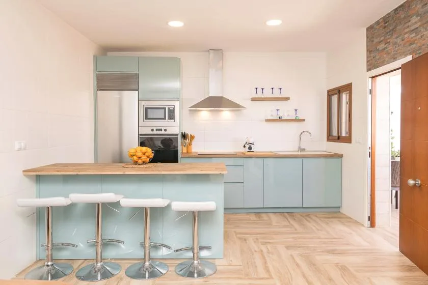 A bright modern kitchen with pale cabinets and a breakfast bar.